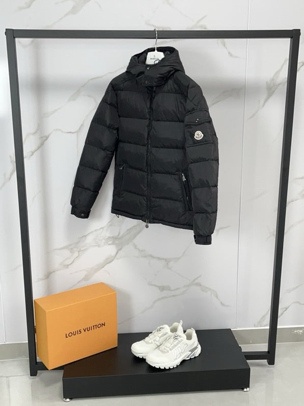 Black long puffer jacket with hood, zip front, and chest pocket seams