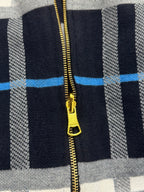 Close-up of Burberry hoodie gold zipper pull on navy plaid knit fabric