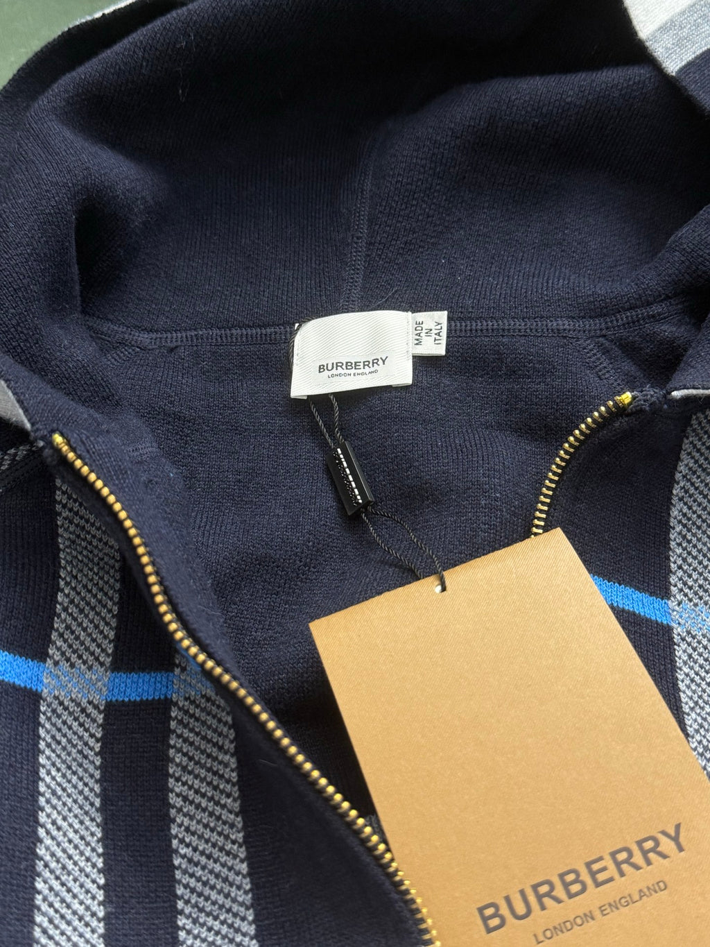 Navy Burberry hoodie neckline and front zipper; gold trim and plaid detail panel