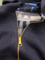 Close-up of navy Burberry hoodie with gold zipper and plaid lining under hood