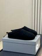 Black suede slip-on sandals with lace-like eyelets and fuzzy lining