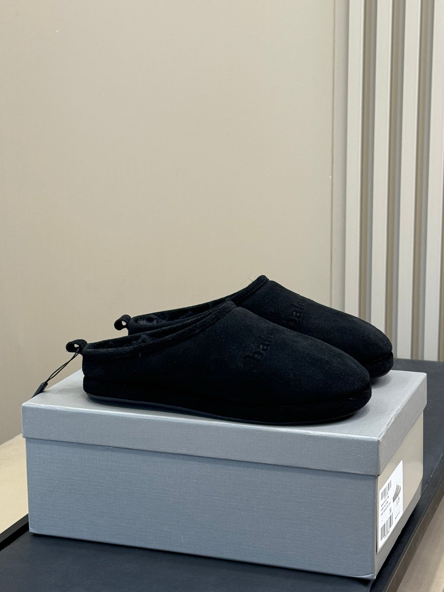 Black suede slip-on sandals with lace-like eyelets and fuzzy lining