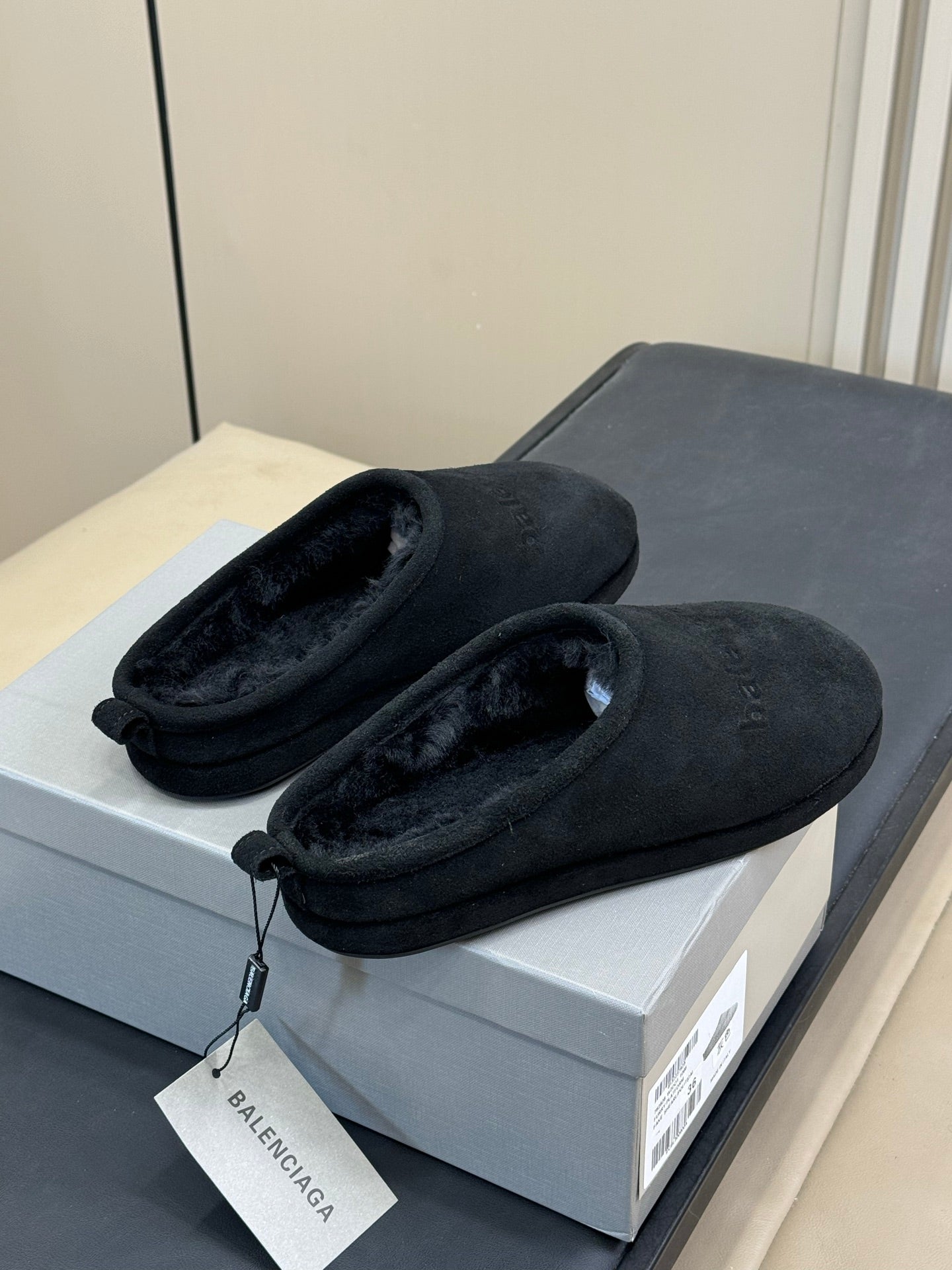 Black suede slip-on mules with plush lining and tag attached