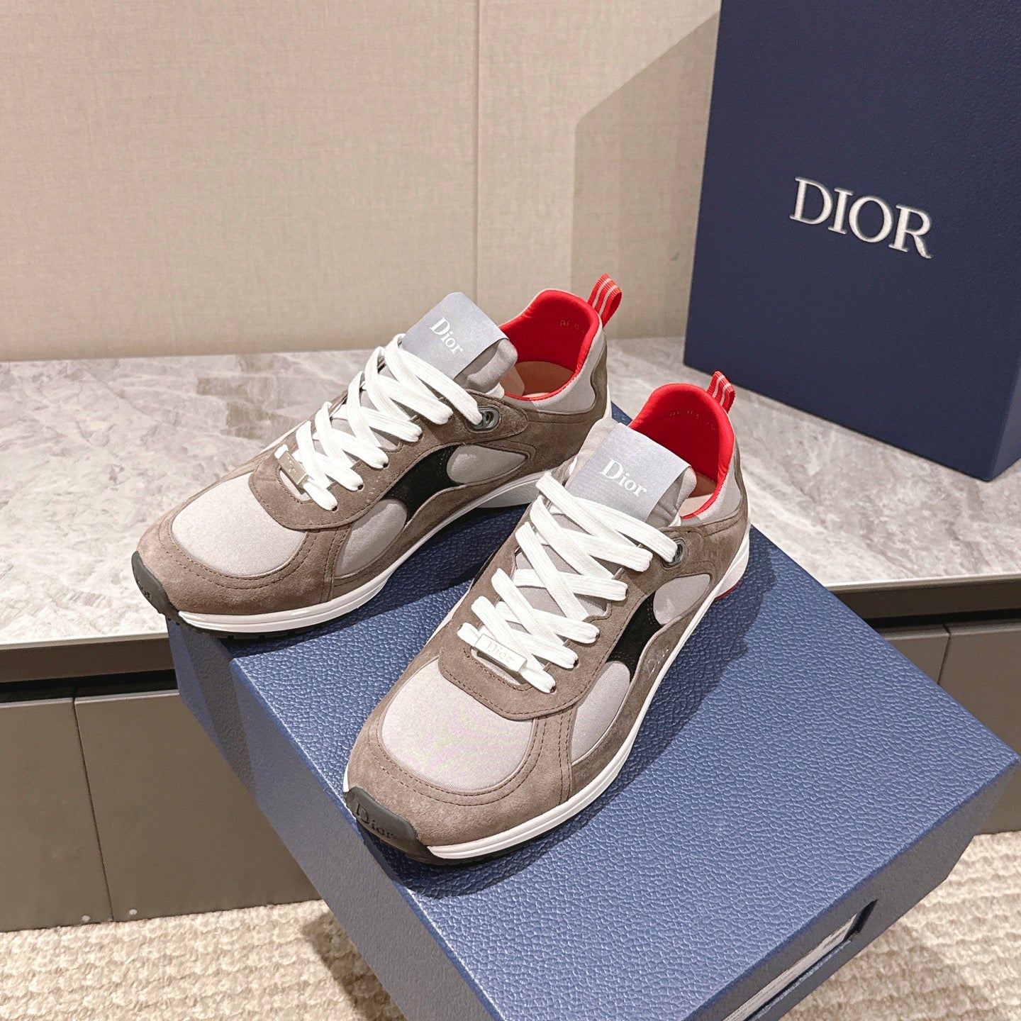 Dior unisex low-top sneakers with beige uppers, white laces, black details, and red lining
