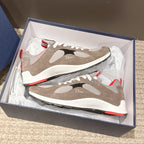 Dior unisex sneakers displayed in box: beige-and-white uppers with black accents and red outsoles