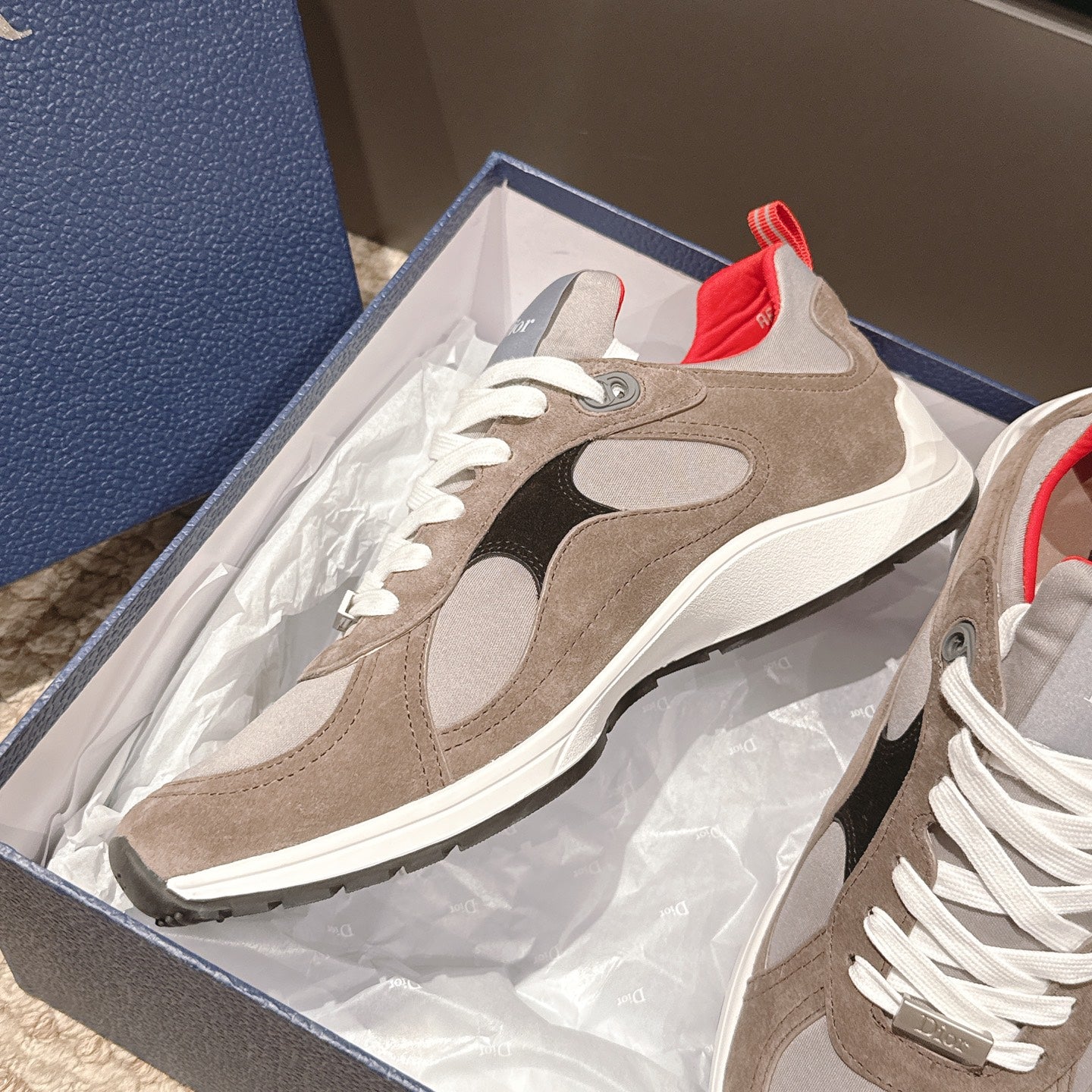 Dior unisex sneakers in a box with beige suede, black side panels, white laces, and red trim