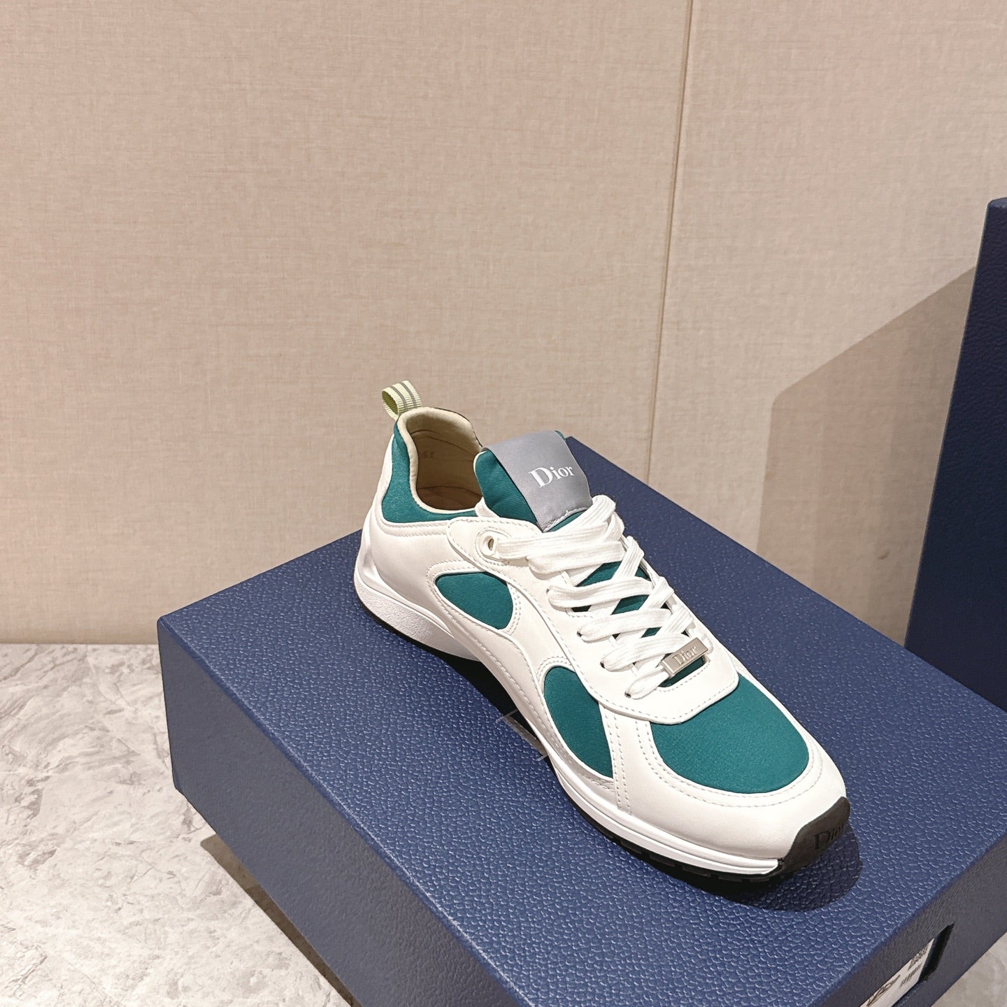 Unisex low-top sneaker on blue box, white with teal oval panels and laces