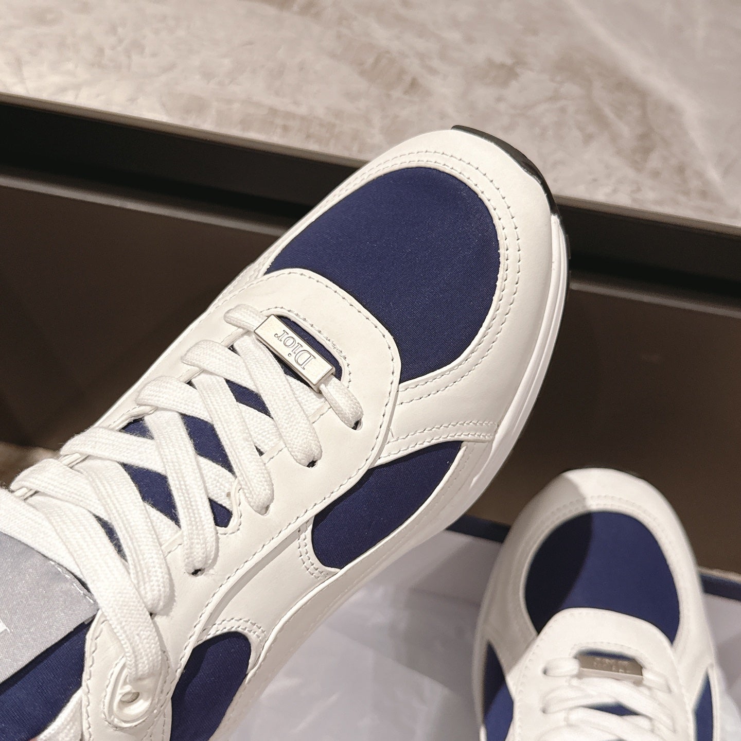 Dior unisex sneakers close-up, white leather with navy side panel and laces