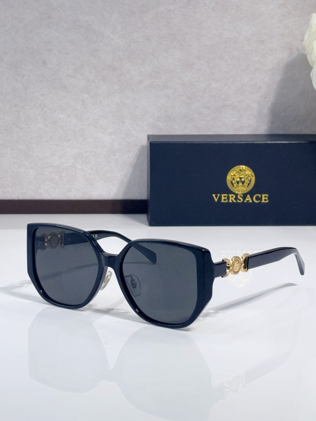 Dark blue sunglasses with rounded lenses and gold logo detail on temples