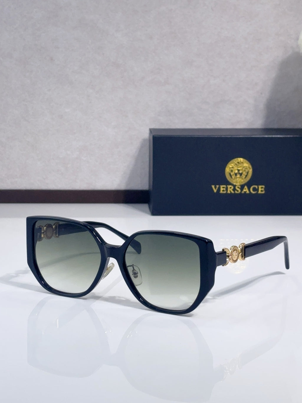 Navy blue sunglasses with rounded lenses and gold logo detail on temples