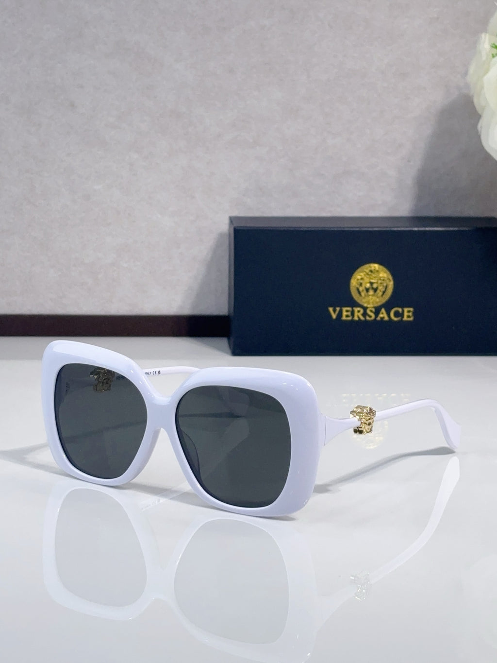 Versace sunglasses with white frames and dark gray-tinted lenses