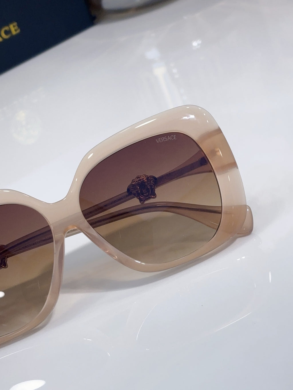 Close-up of Versace sunglasses: beige frame and brown-tinted lens
