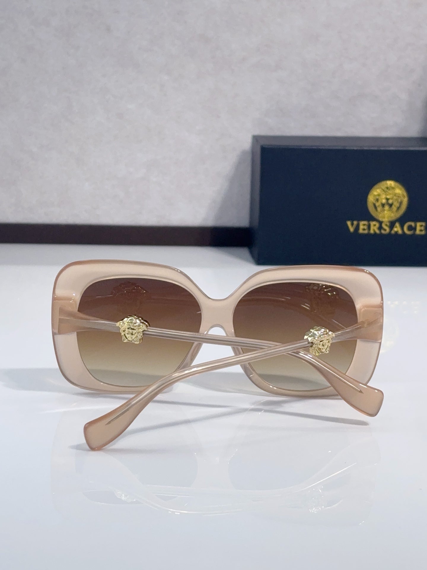 Versace sunglasses with light beige frames and amber-tinted lenses