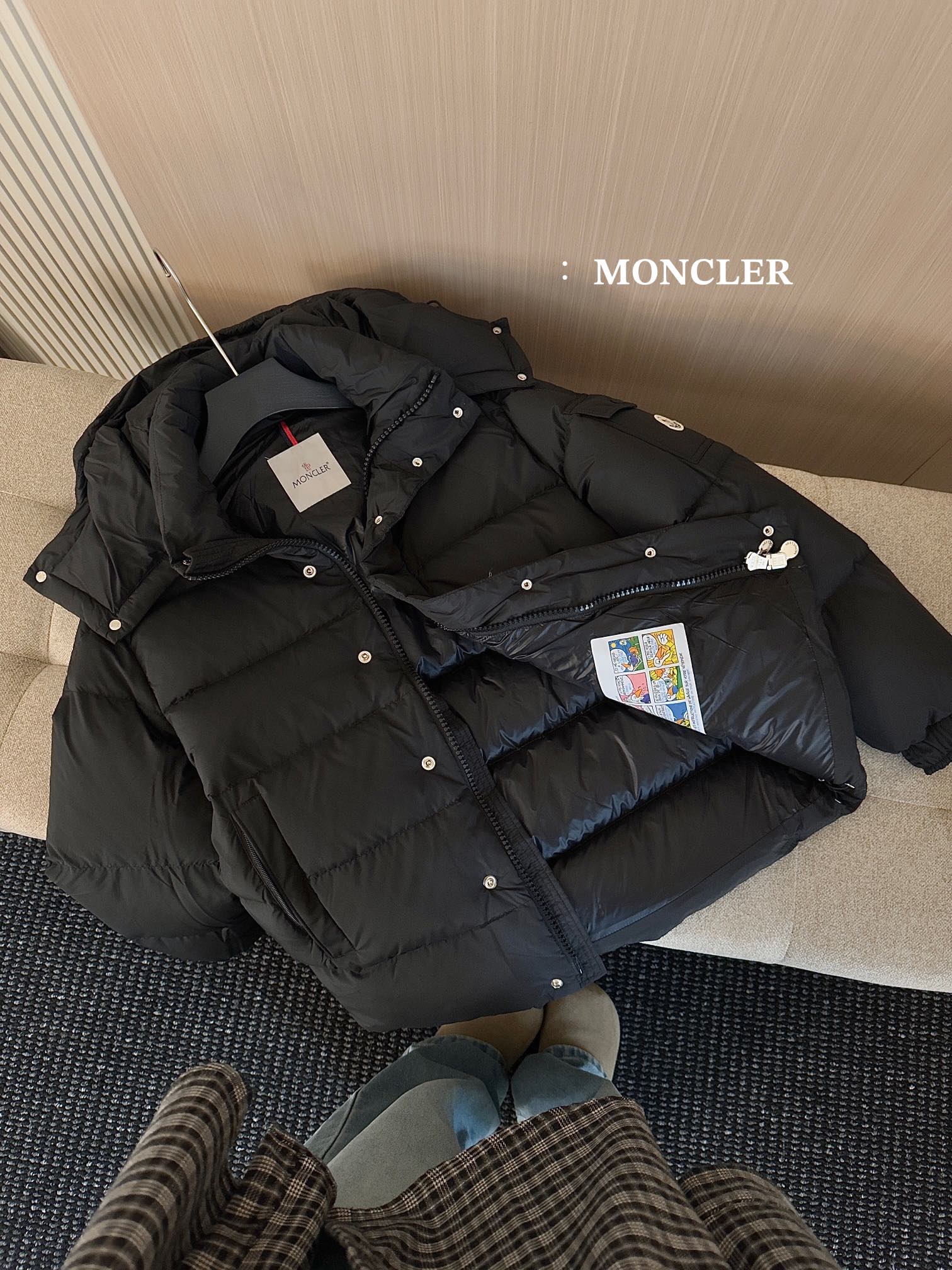 Black hooded puffer jacket with zipper, snap buttons, and hanging price tag