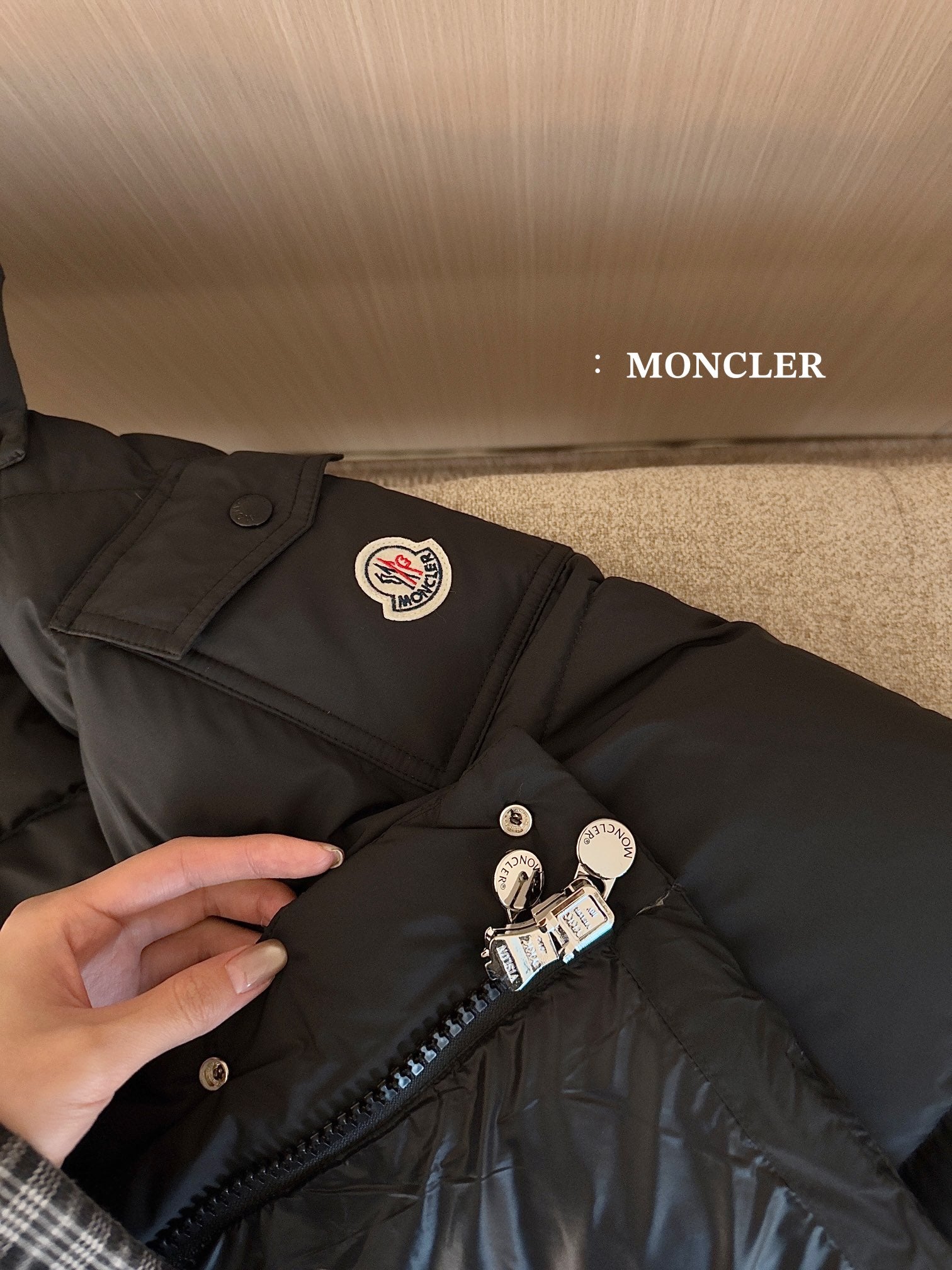Black puffer jacket chest pocket and zipper pull with circular logo patch