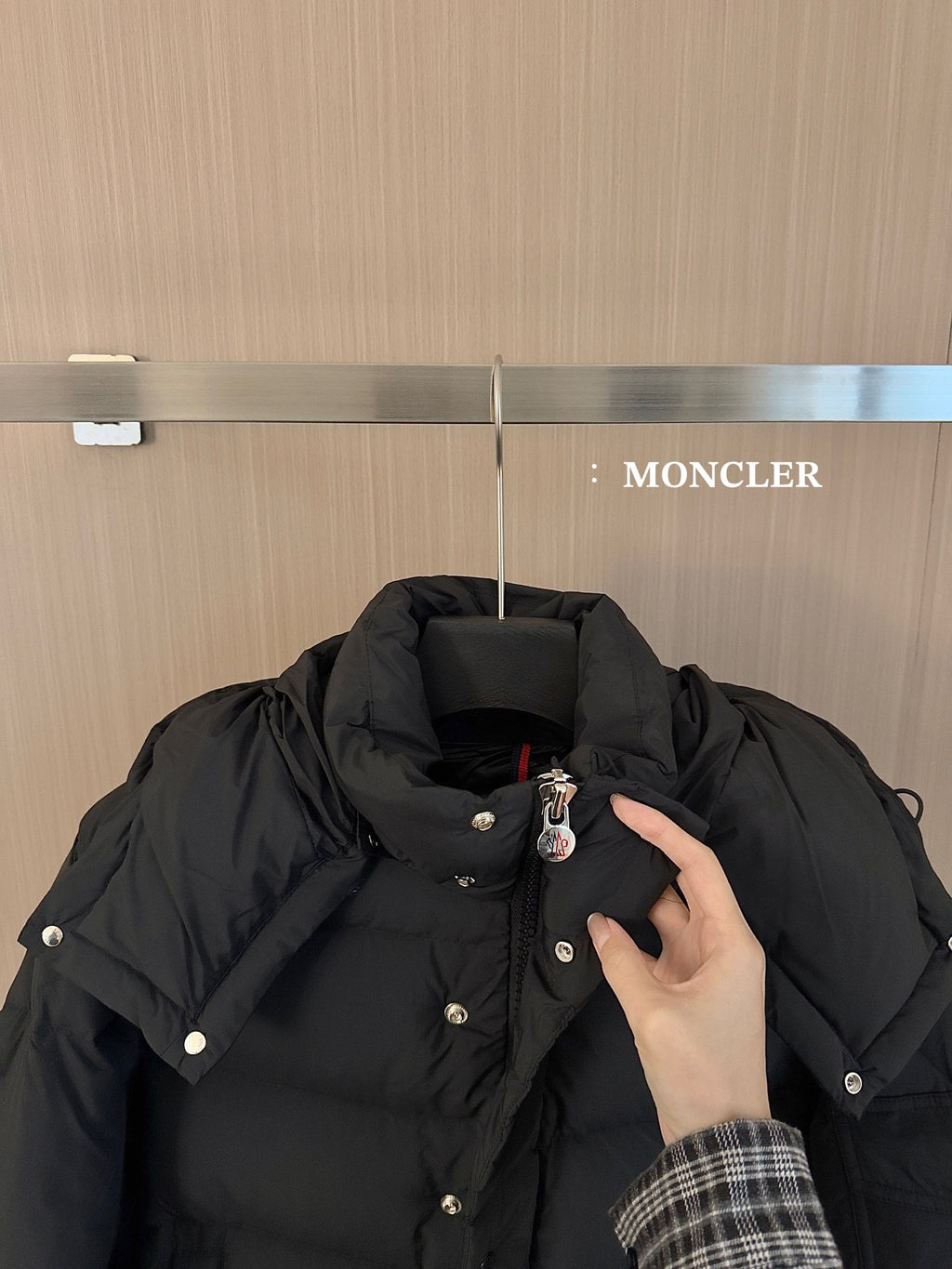 Black puffer jacket collar and hood with snap buttons and small logo pin