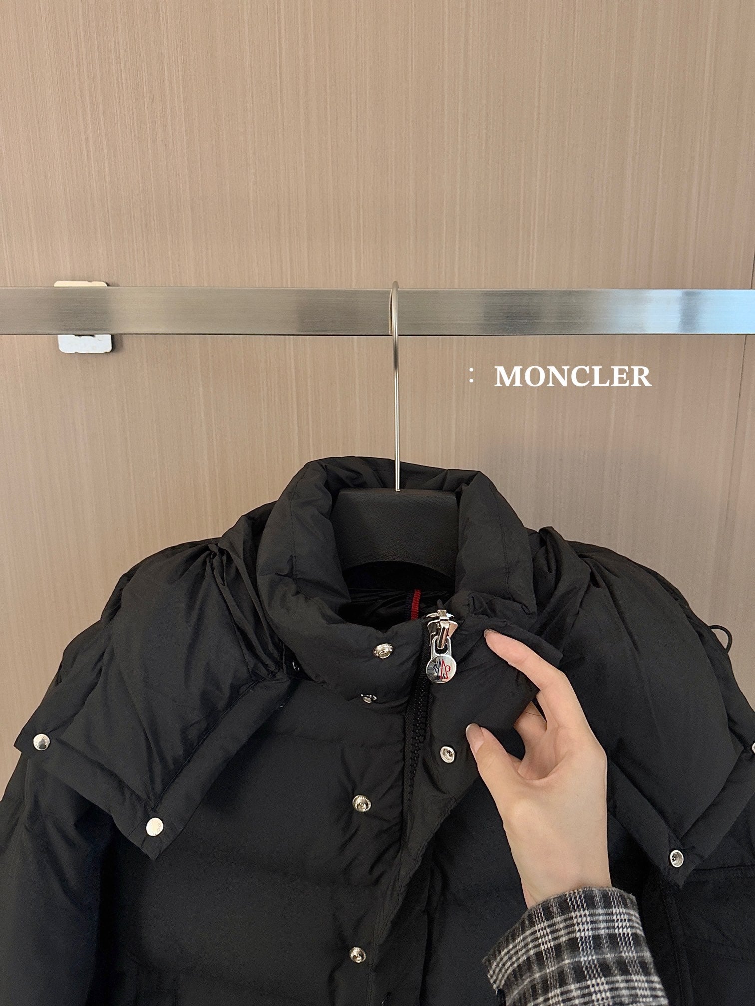 Black puffer jacket collar and hood with snap buttons and small logo pin