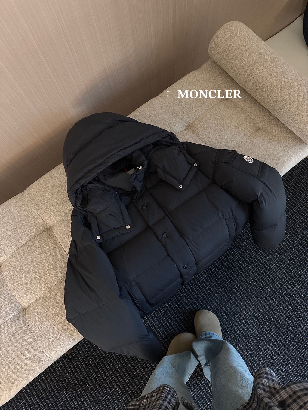 Black hooded puffer jacket on sofa with snap buttons and inner lining