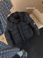 Black hooded puffer jacket on floor with quilted panels and snap button closure