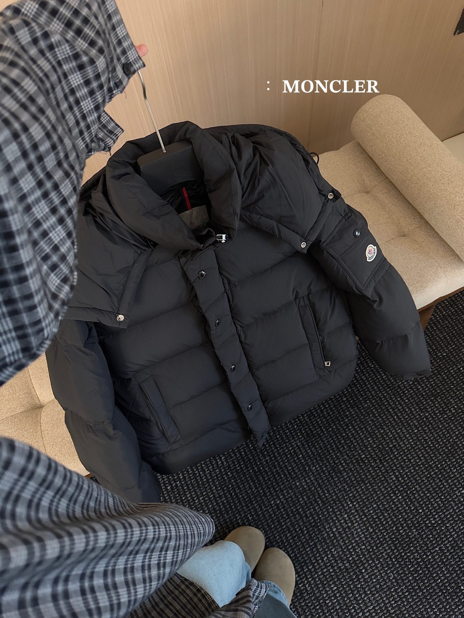 Black hooded puffer jacket on floor with quilted panels and snap button closure