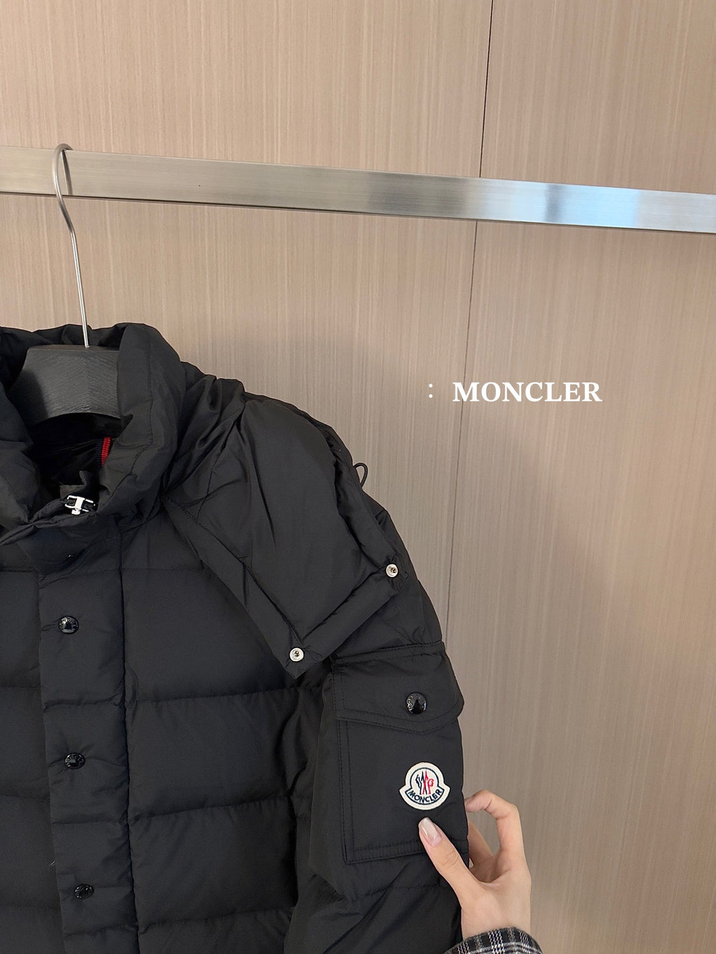 Black puffer jacket shoulder and sleeve with snap buttons and circular logo patch