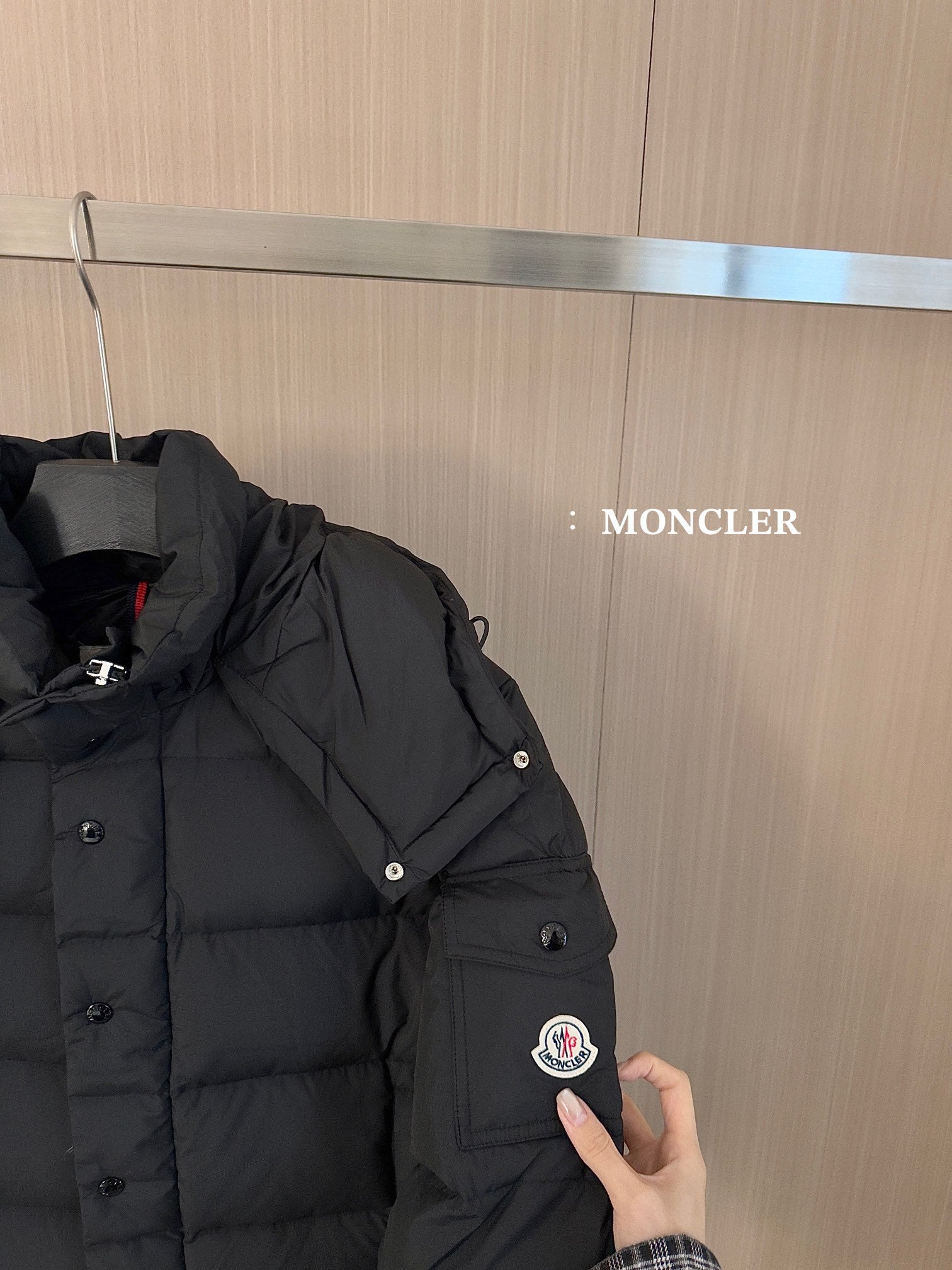 Black puffer jacket shoulder and sleeve with snap buttons and circular logo patch