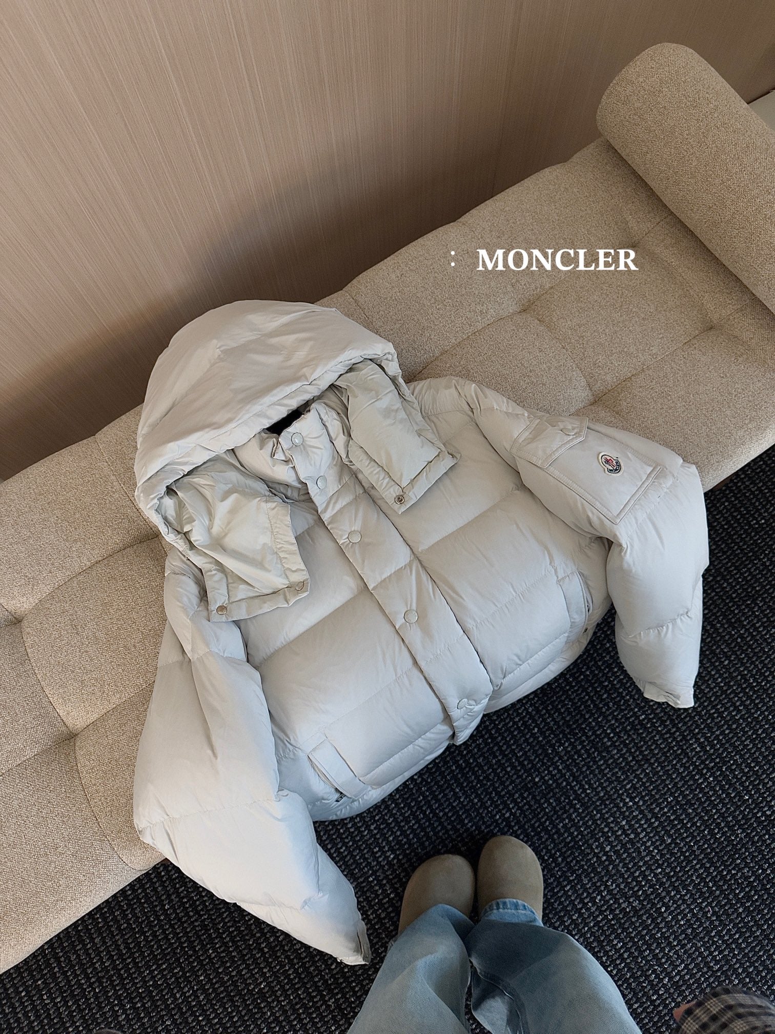 Moncler long white puffer jacket laid on side, hood and snap-button placket visible
