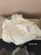White long puffer jacket on sofa cushion, front view with hood and buttons