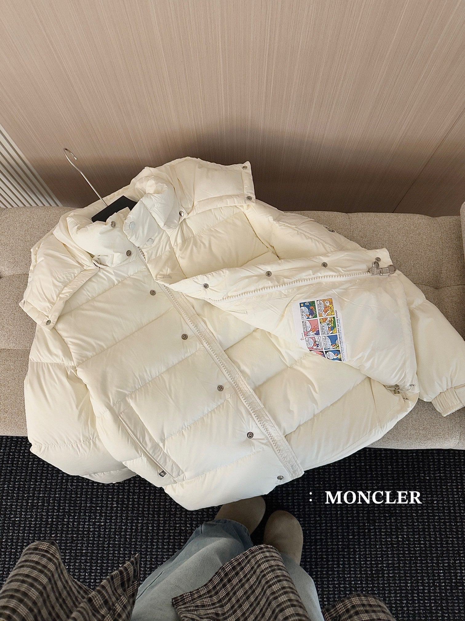 White long puffer jacket on sofa cushion, front view with hood and buttons