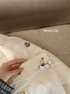 White long puffer jacket close-up: zip front, snap buttons, chest logo patch