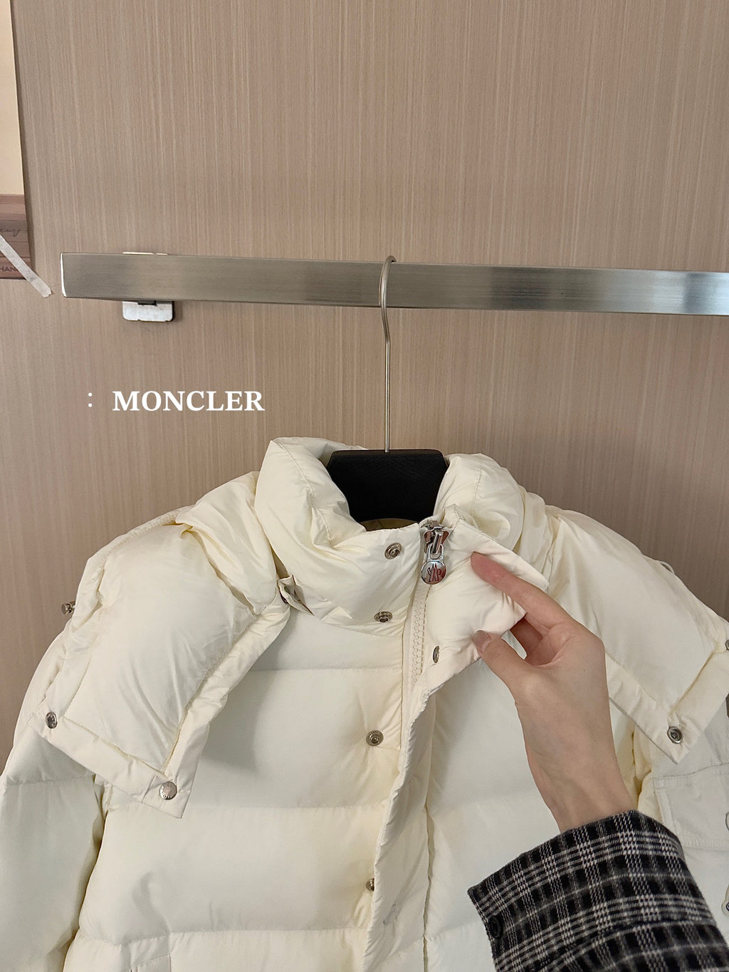 White long puffer jacket hood and shoulder detail with button placket, held by hand
