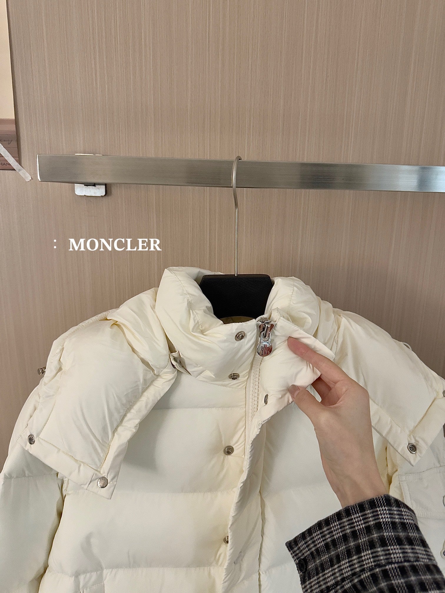 White long puffer jacket hood and shoulder detail with button placket, held by hand