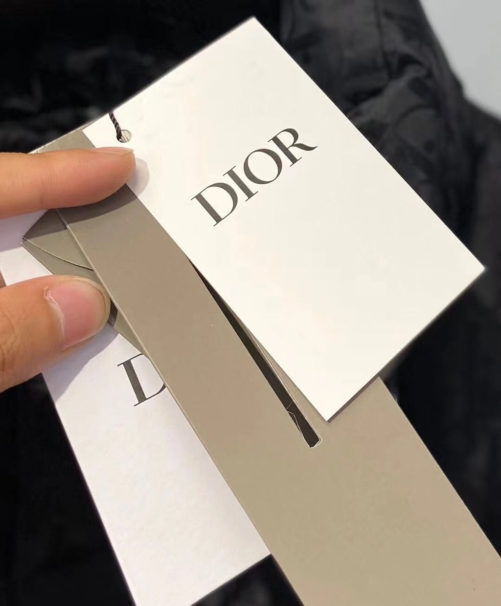 Dior hang tag on white paper attached to black fabric