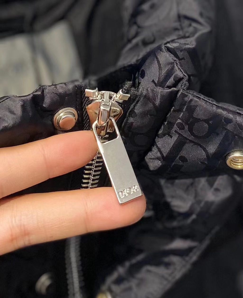Dior zipper pull and ring hardware on black puffer jacket fabric