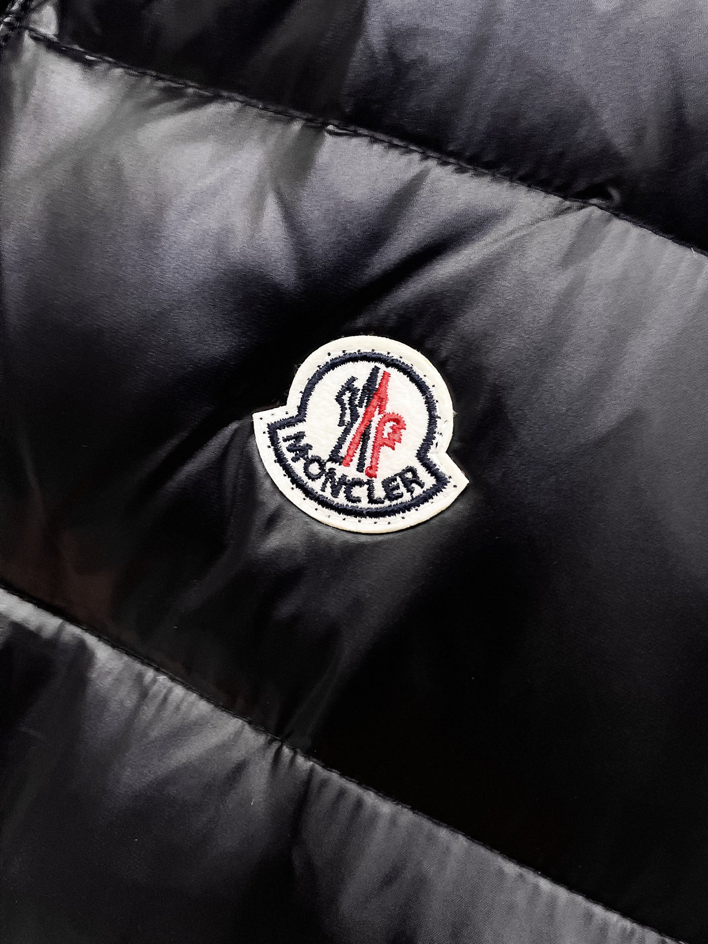 Moncler round logo patch on black quilted puffer vest fabric