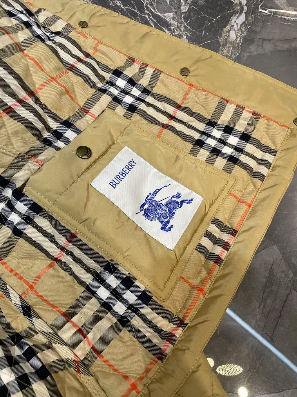 Plaid quilt lining with Burberry logo patch on quilted jacket front panel