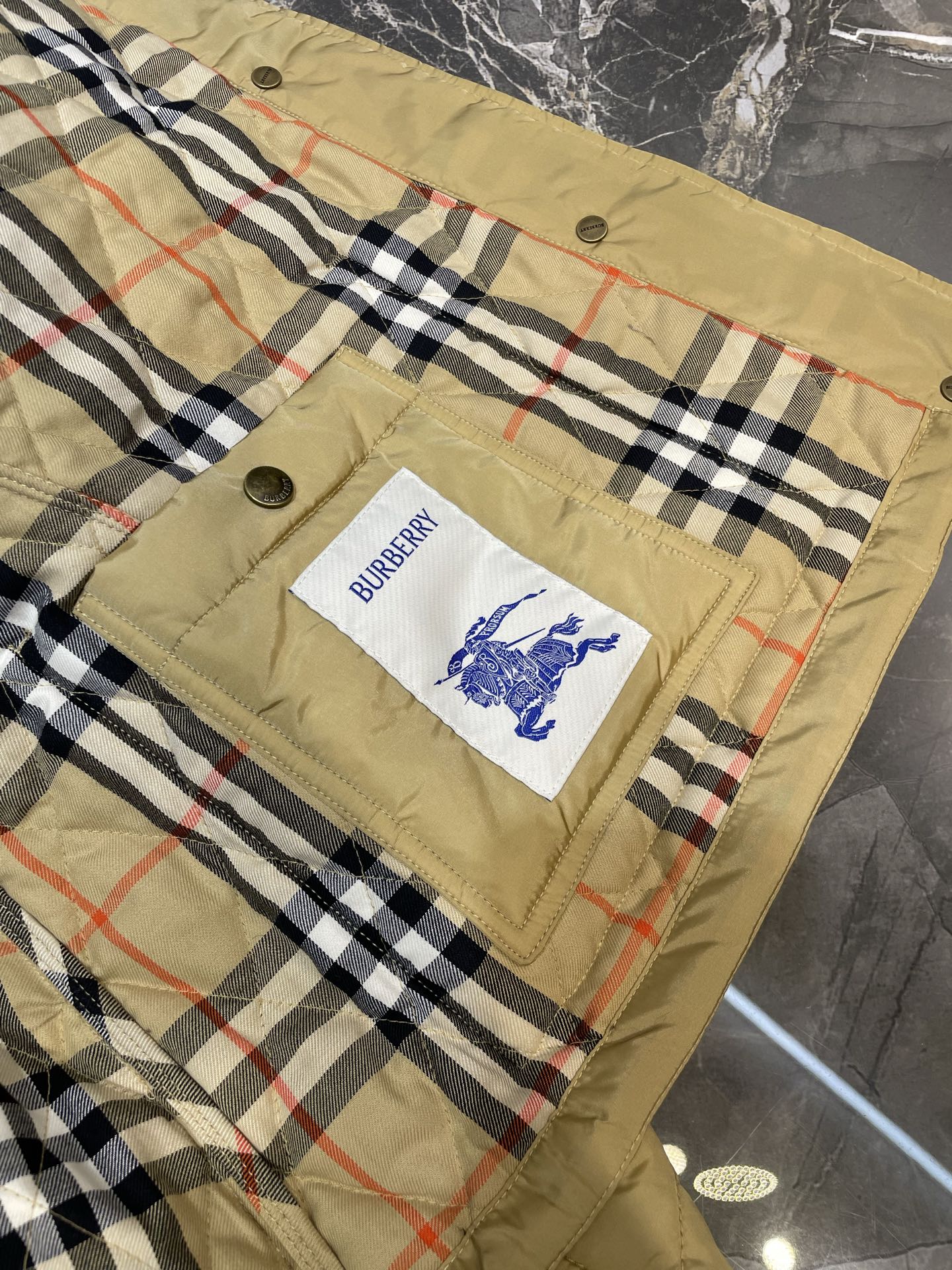 Plaid quilt lining with Burberry logo patch on quilted jacket front panel