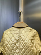 Back view of light yellow quilted jacket with stand collar and buttoned center seam