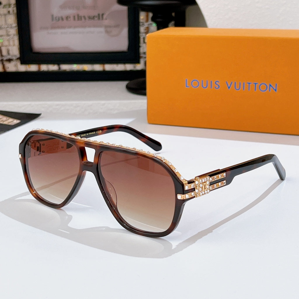 Sunglasses with dark frames and tinted lenses; rhinestone logo detail on temple band