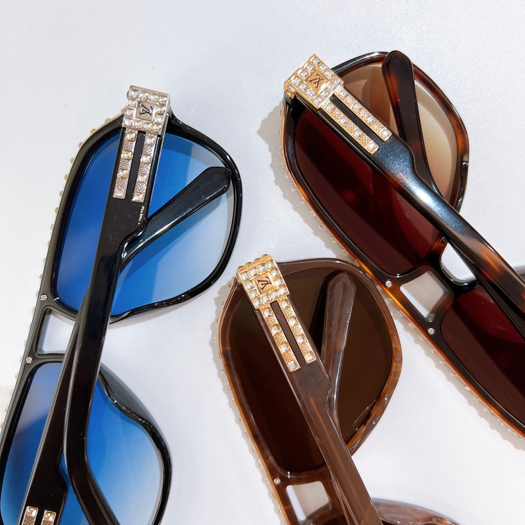 Pair of sunglasses with blue and brown lenses; rhinestone logo detail on temple straps