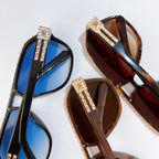 Pair of sunglasses with blue and brown lenses; rhinestone logo detail on temple straps