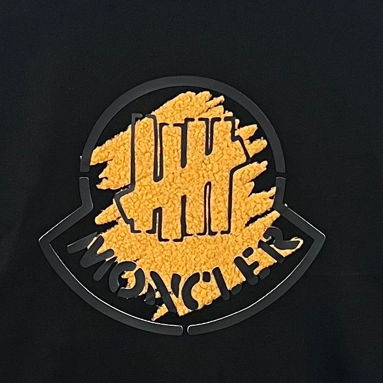 Black Moncler long-sleeve top close-up of circular logo graphic embroidery