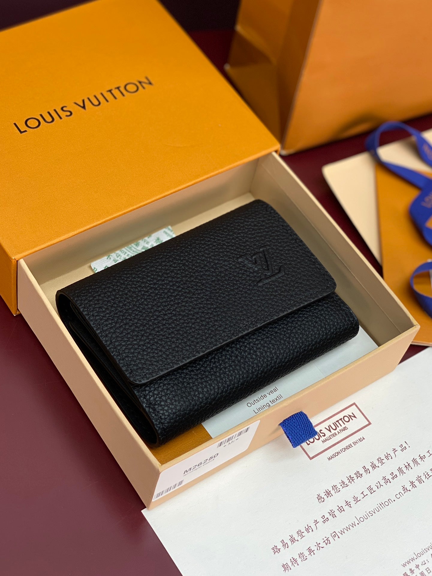 Black textured leather small bag with front flap and small emblem detail.
