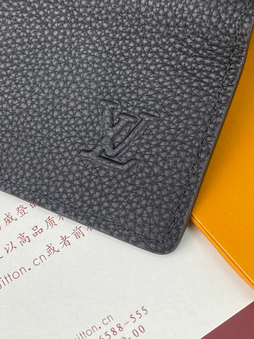 Black textured leather small bag with embossed LV logo on front panel.