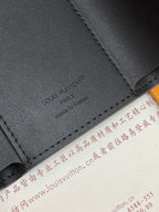 Black textured leather small bag corner with embossed logo and contrast stitching.