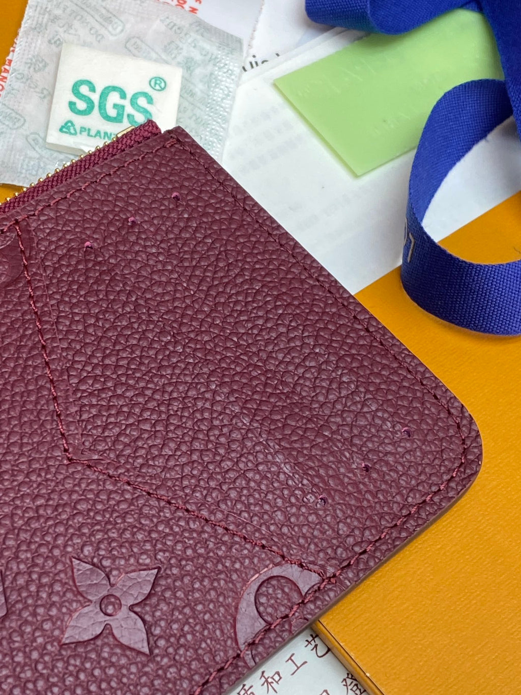 Burgundy monogram leather pouch with stitched details and gold zipper edge
