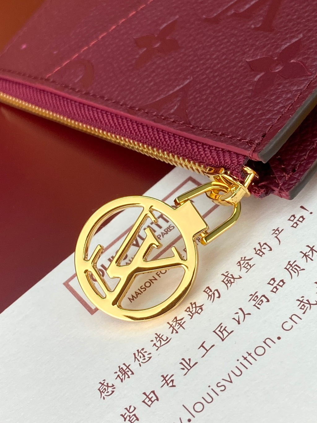 Burgundy monogram pouch bag with gold-tone zipper pull and LV charm