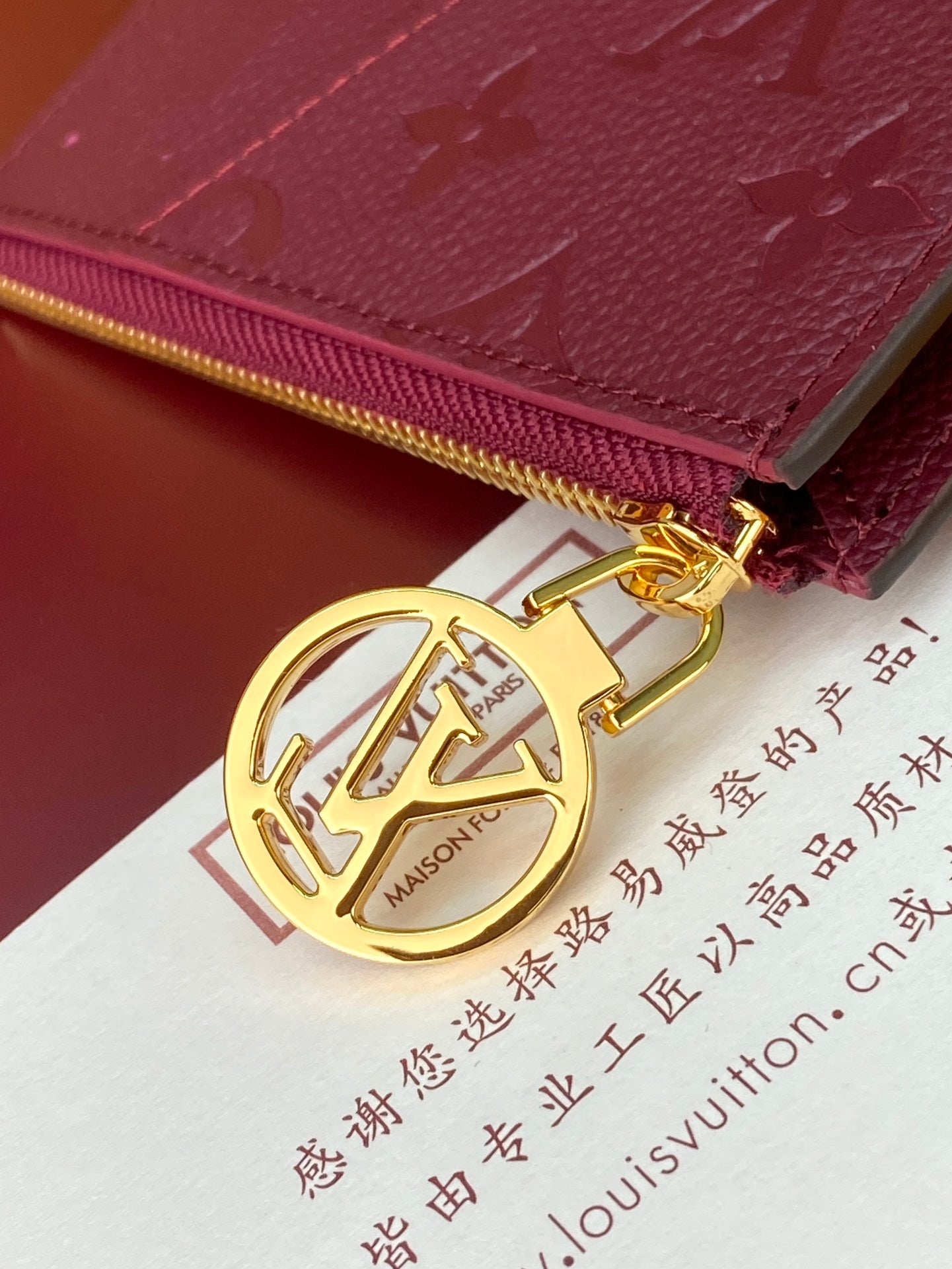 Burgundy monogram pouch bag with gold-tone zipper pull and LV charm