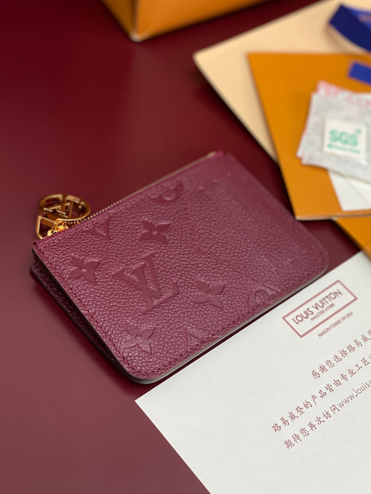 Small leather pouch bag in burgundy with monogram pattern and gold zipper