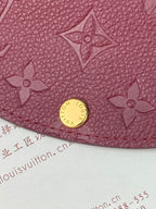 Small Louis Vuitton monogram bag close-up with gold snap and embossed flower motifs, dark plum